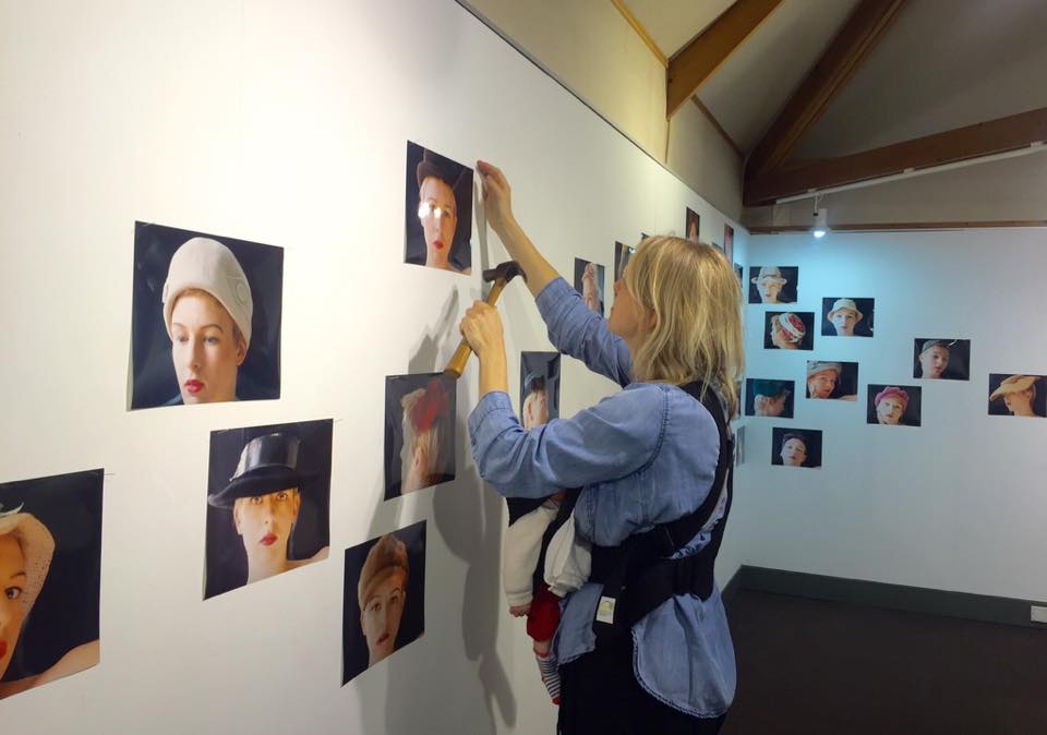 Hanging exhibition 'Mrs. West's Hats' with her great-granddaughter
